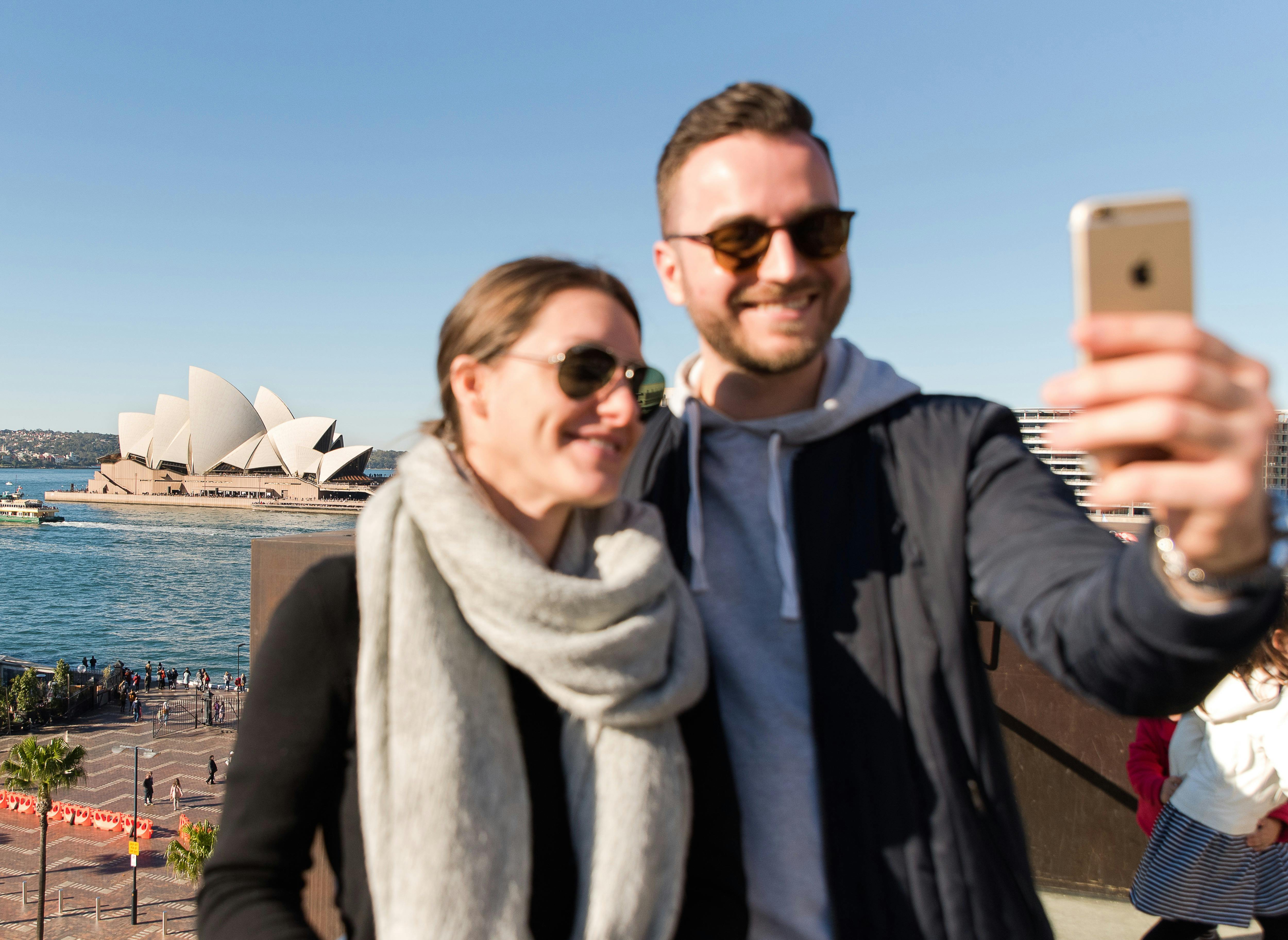 Young couple with selfie smart phone Opera House background