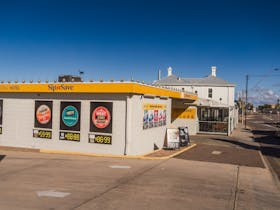 Exterior view of the Sipu2019n Save outlet at the Pastoral Hotel Motel featuring promotional signs.