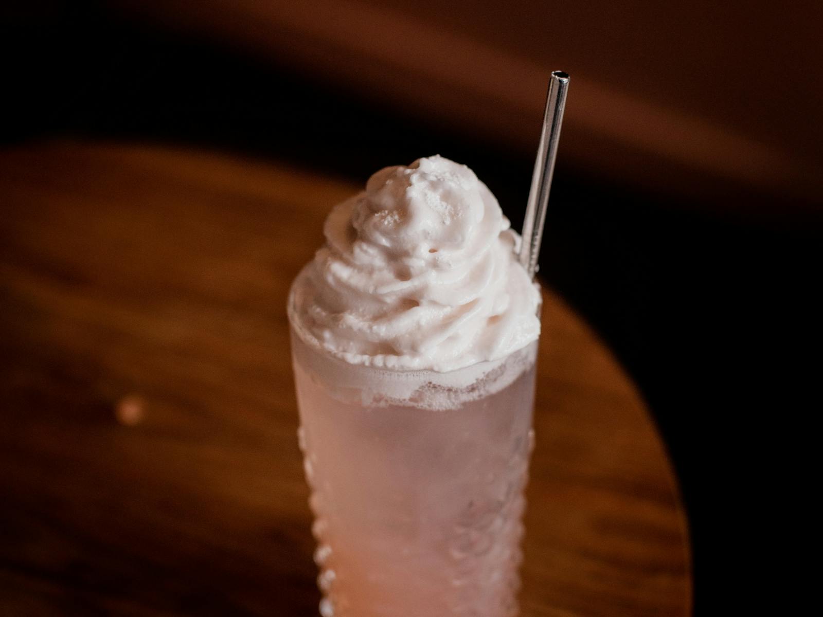 Gin and raspberry cocktail, served in a highball glass, pink in colour with a meringue foam