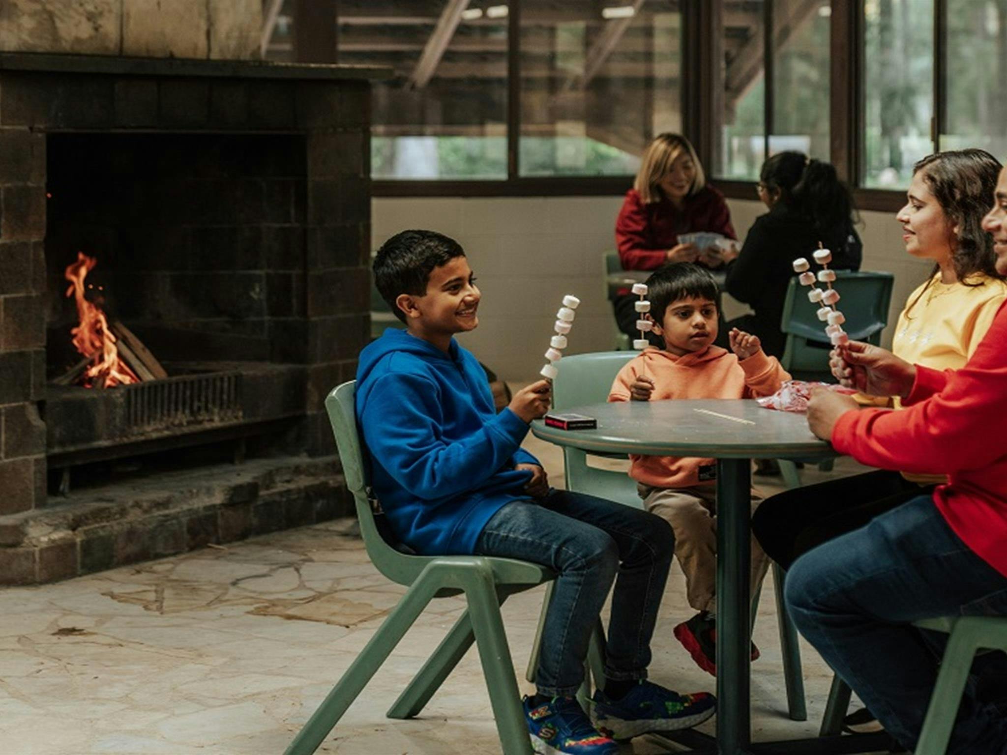 A family having fun preparing marshmallows to roast over an open fire at the Barmah communal dining