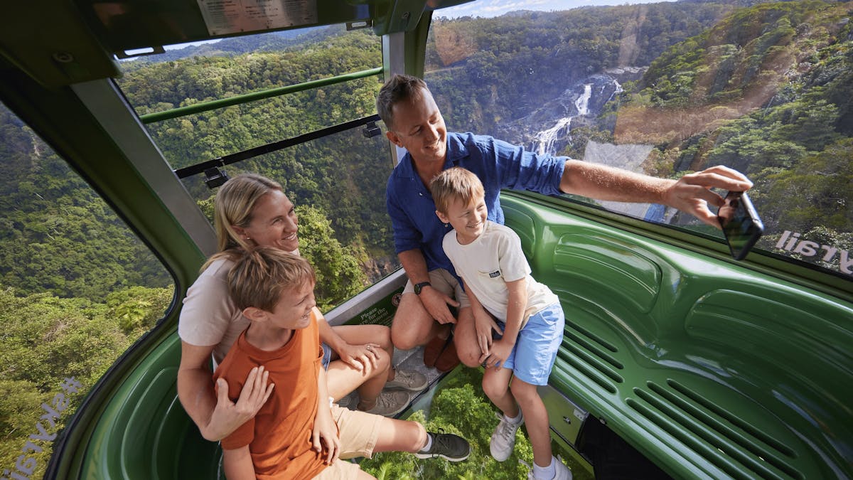 Family in Diamond View gondola over the rainforest taking a selfie with Barron Falls behind
