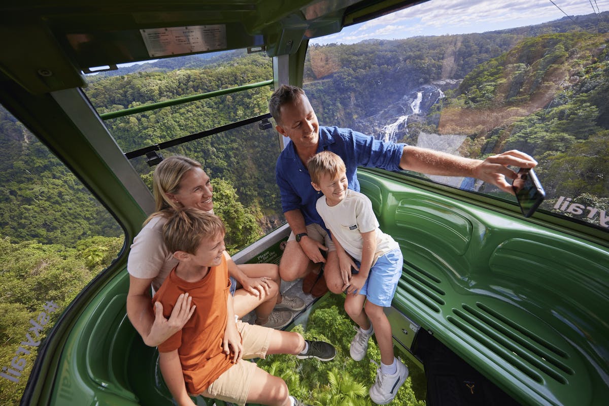 Family in Diamond View gondola over the rainforest taking a selfie with Barron Falls behind