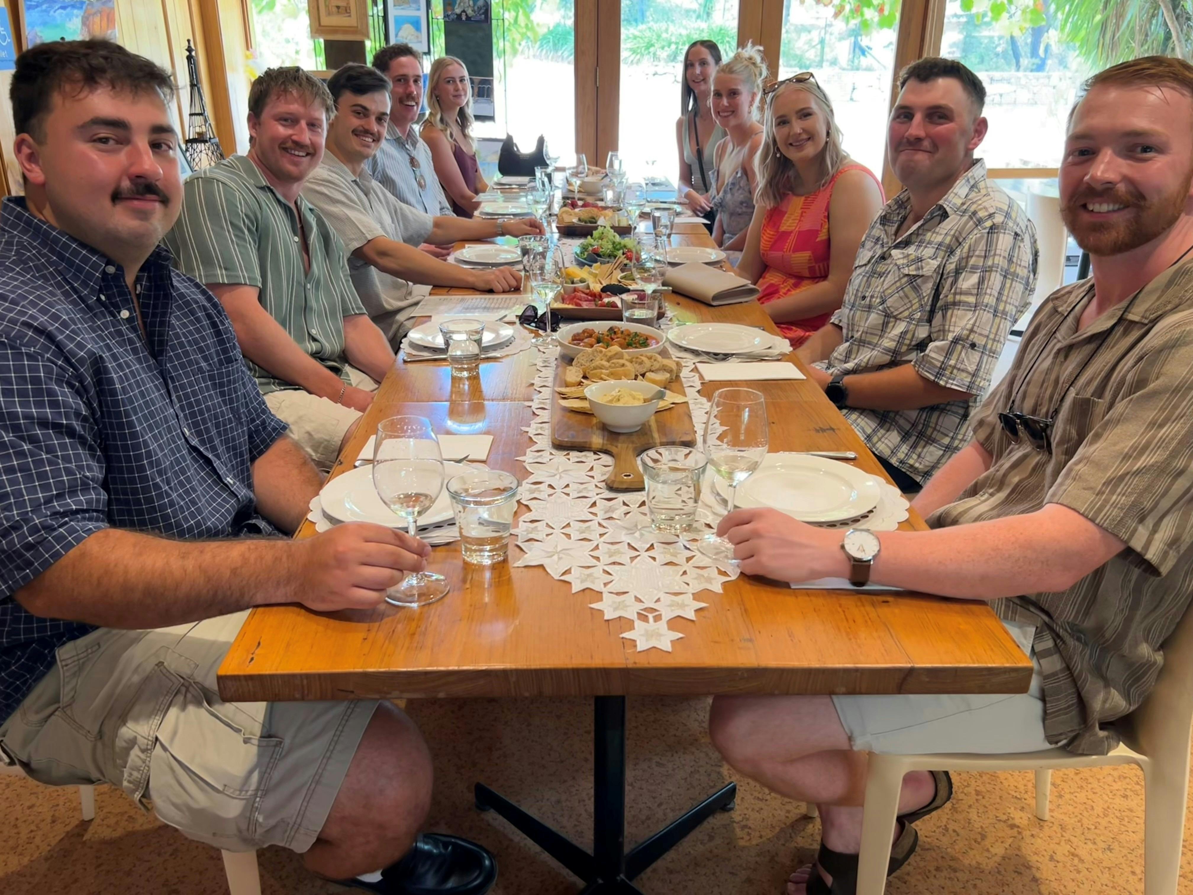 A group of people at a long table with platters of food