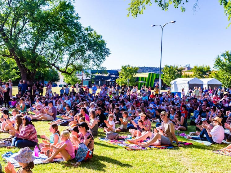 Audiences sit outdoors on the grass at QEII Square, Albury during Borderville 2022.