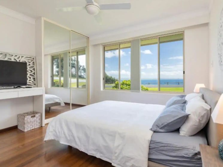 Bedroom with ceiling fan, mirrored built in wardrobe, TV, ocean views