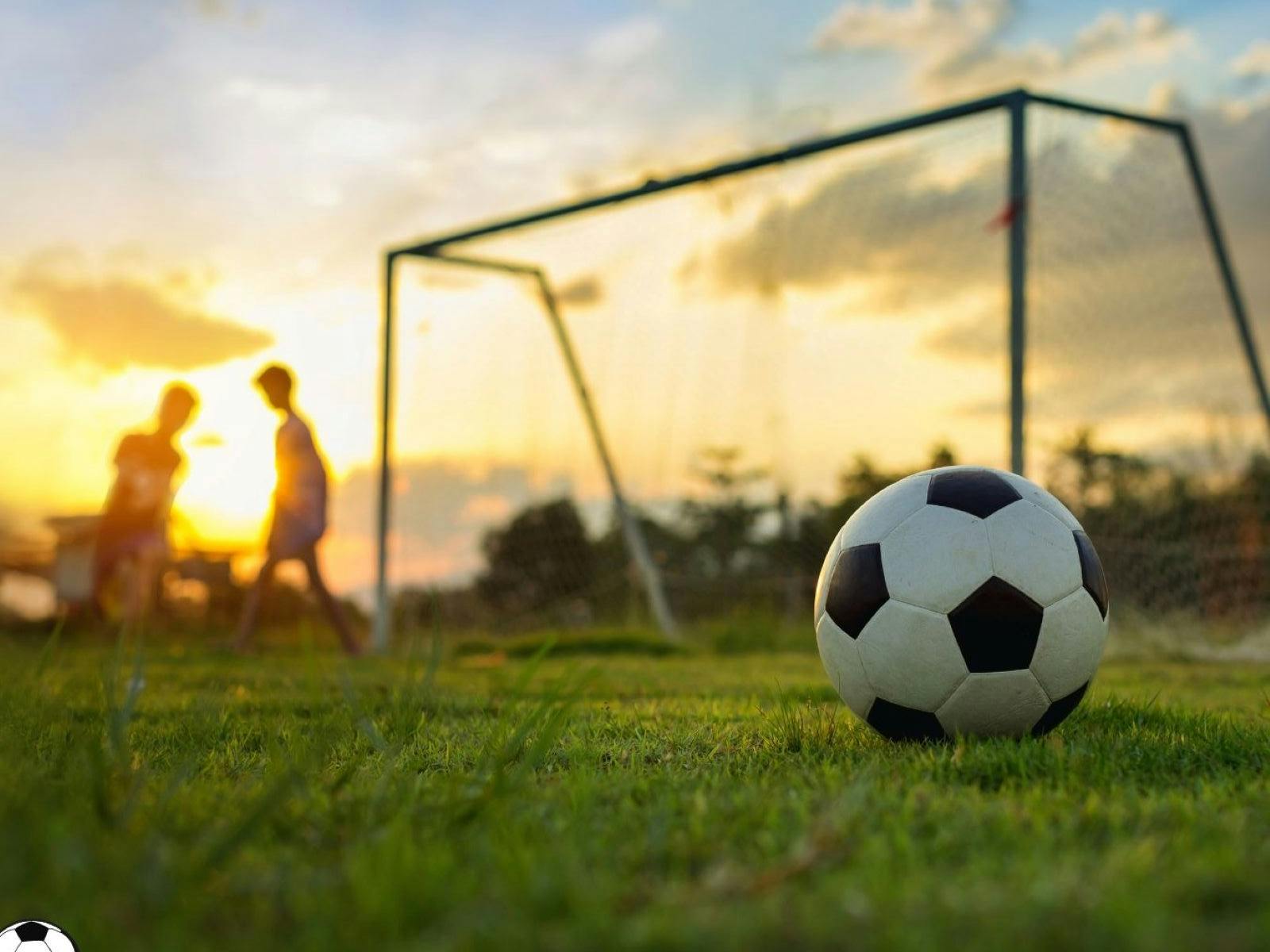 Sunset football goal with people playing