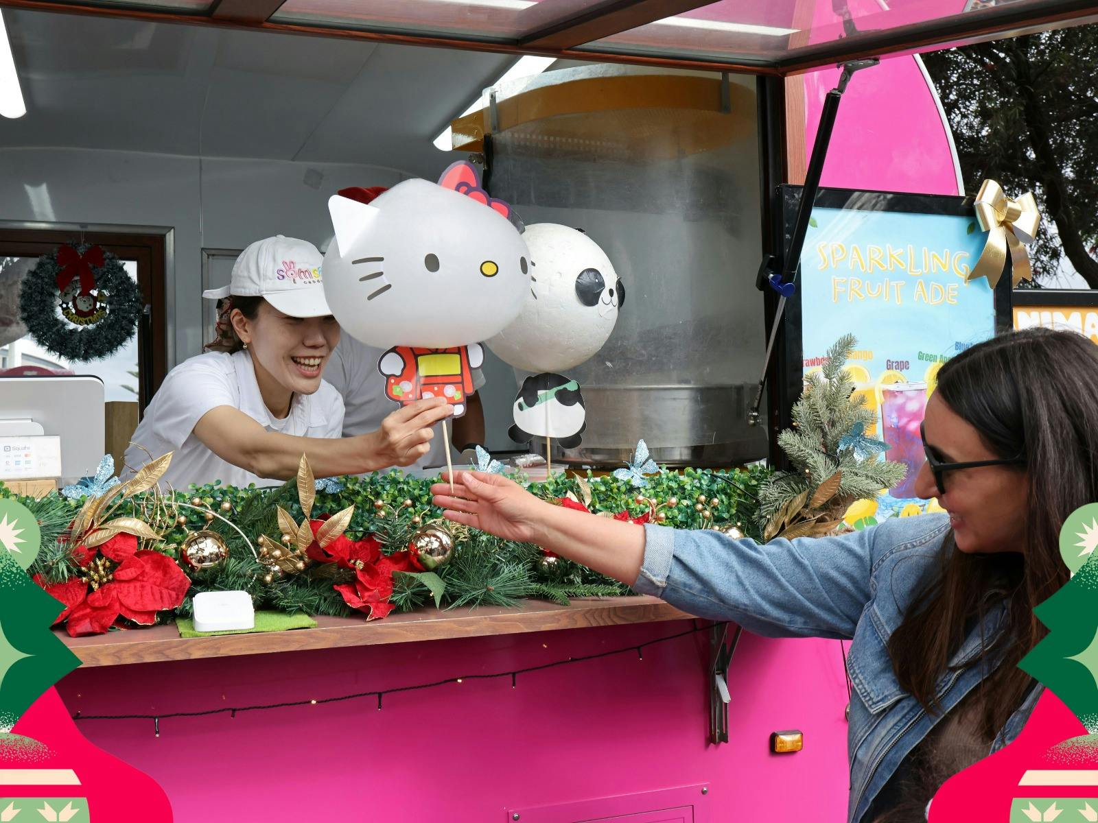 Festivalgoer purchases a festive treat from a decorated food stall at the Christmas festival.