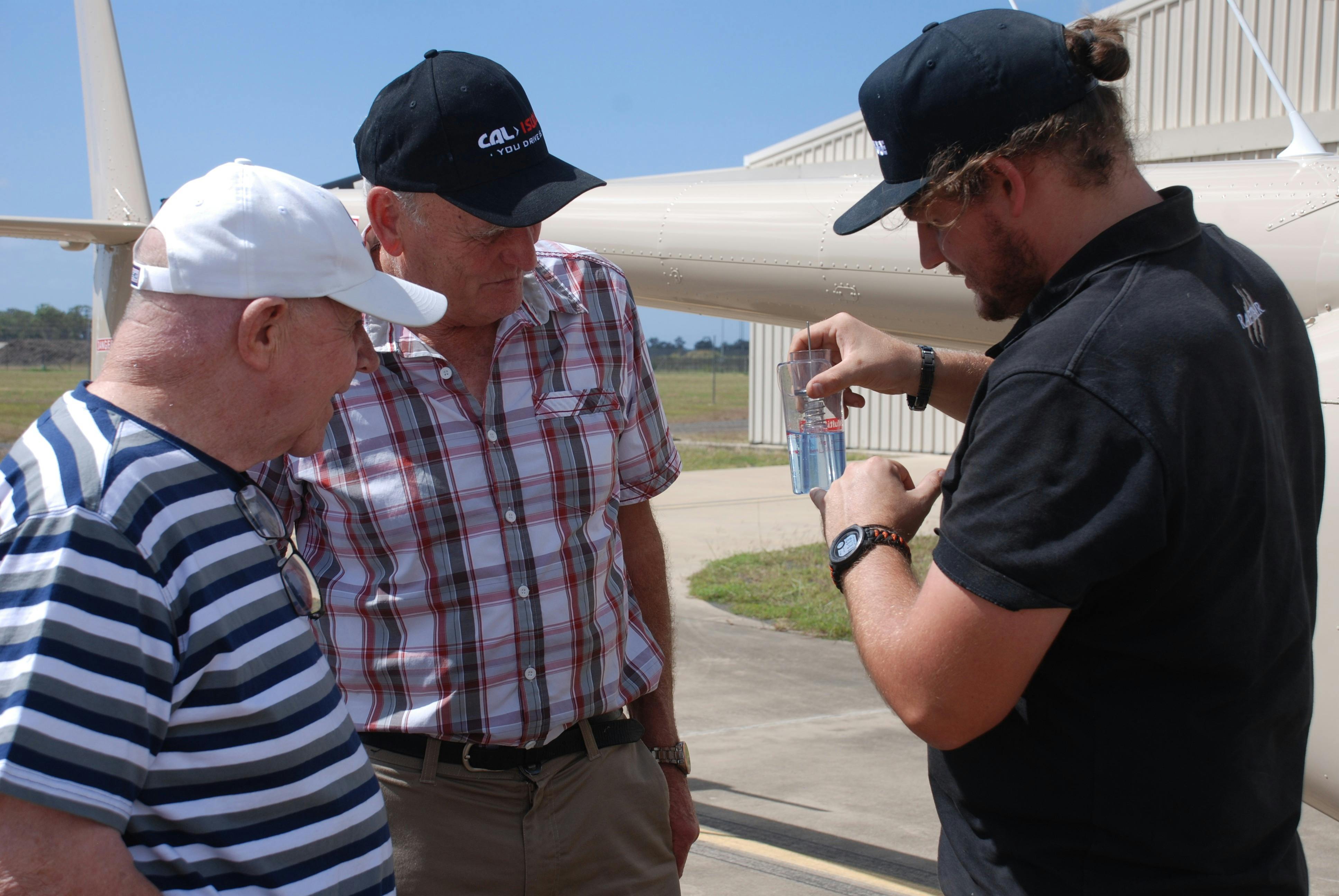The pilot is showing the guests on a VIP tour how to screen the fuel for water in the safety checks