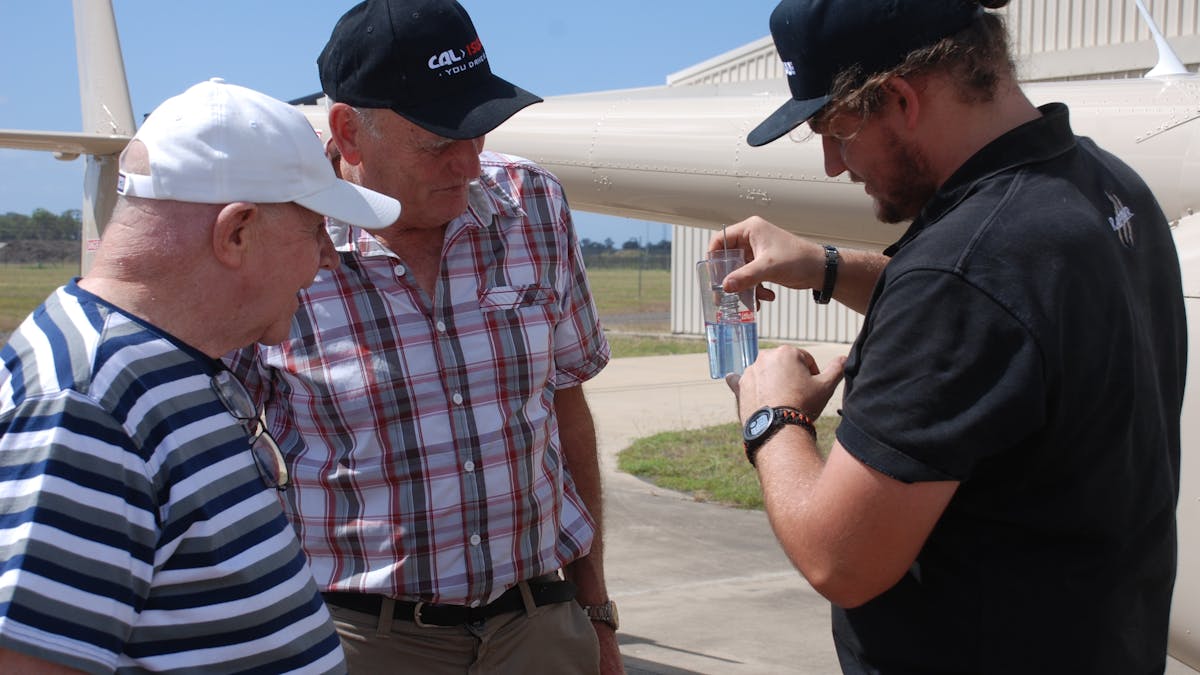 The pilot is showing the guests on a VIP tour how to screen the fuel for water in the safety checks