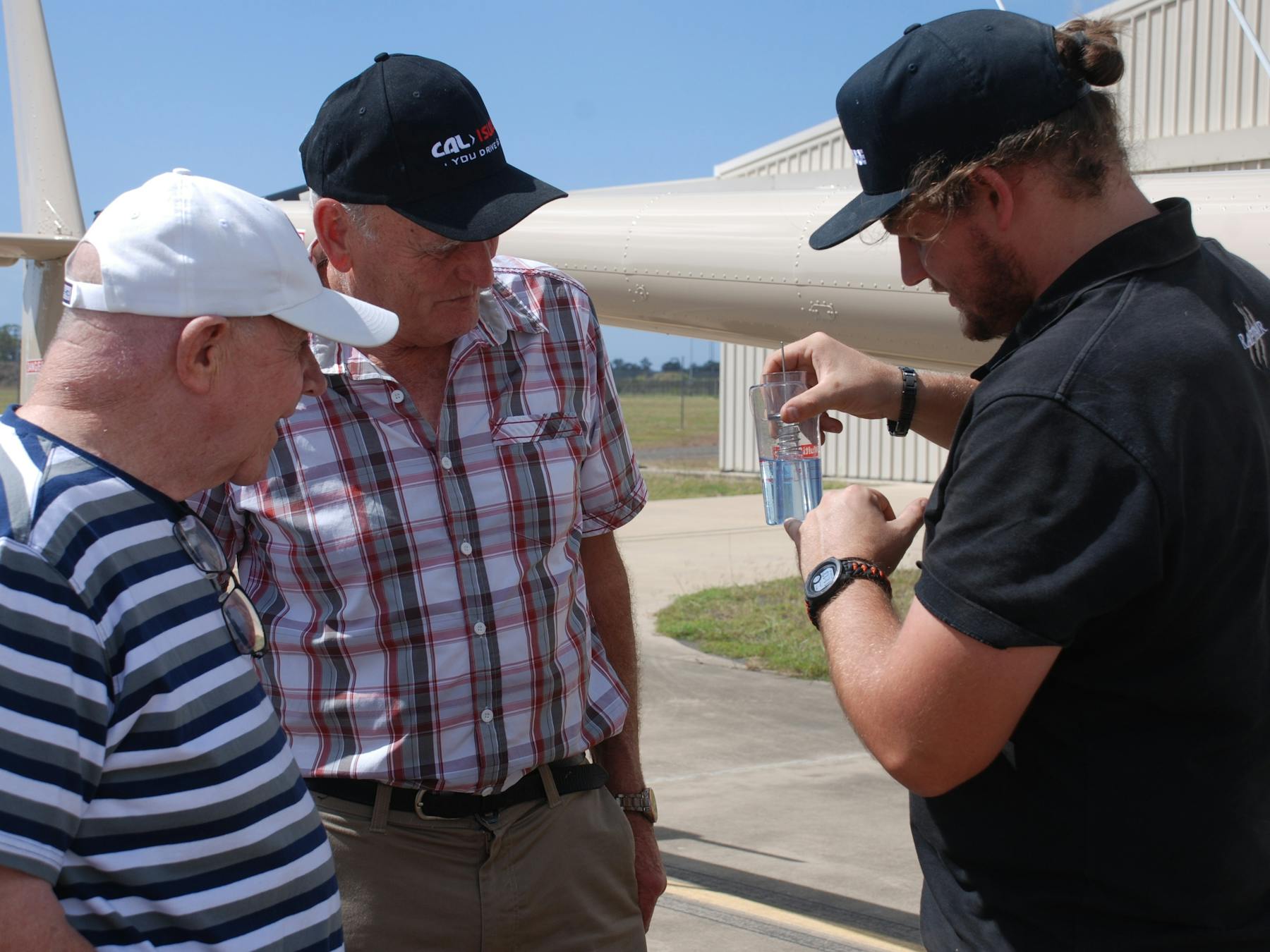 The pilot is showing the guests on a VIP tour how to screen the fuel for water in the safety checks