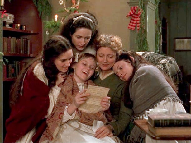 Still from Little Women showing a group of girls gathered around a woman reading a letter