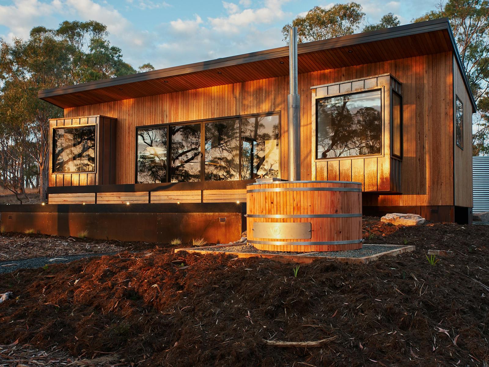 Blue Gum clad exterior cabin in bush setting with woodfired hot tub