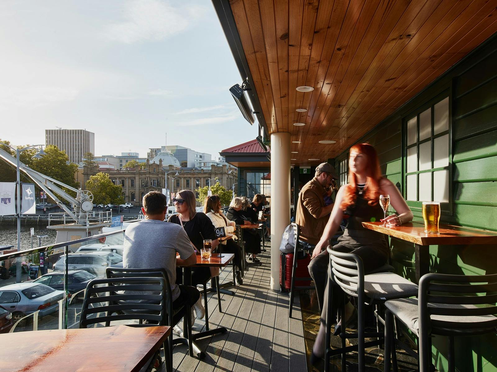 Kelp Bar's sunny outside balcony, with patrons seated at low and high tables.