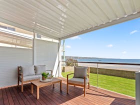 View of Beachfront Apartment 2 from on the deck, shows deck lounge, chair, coffee table, and view