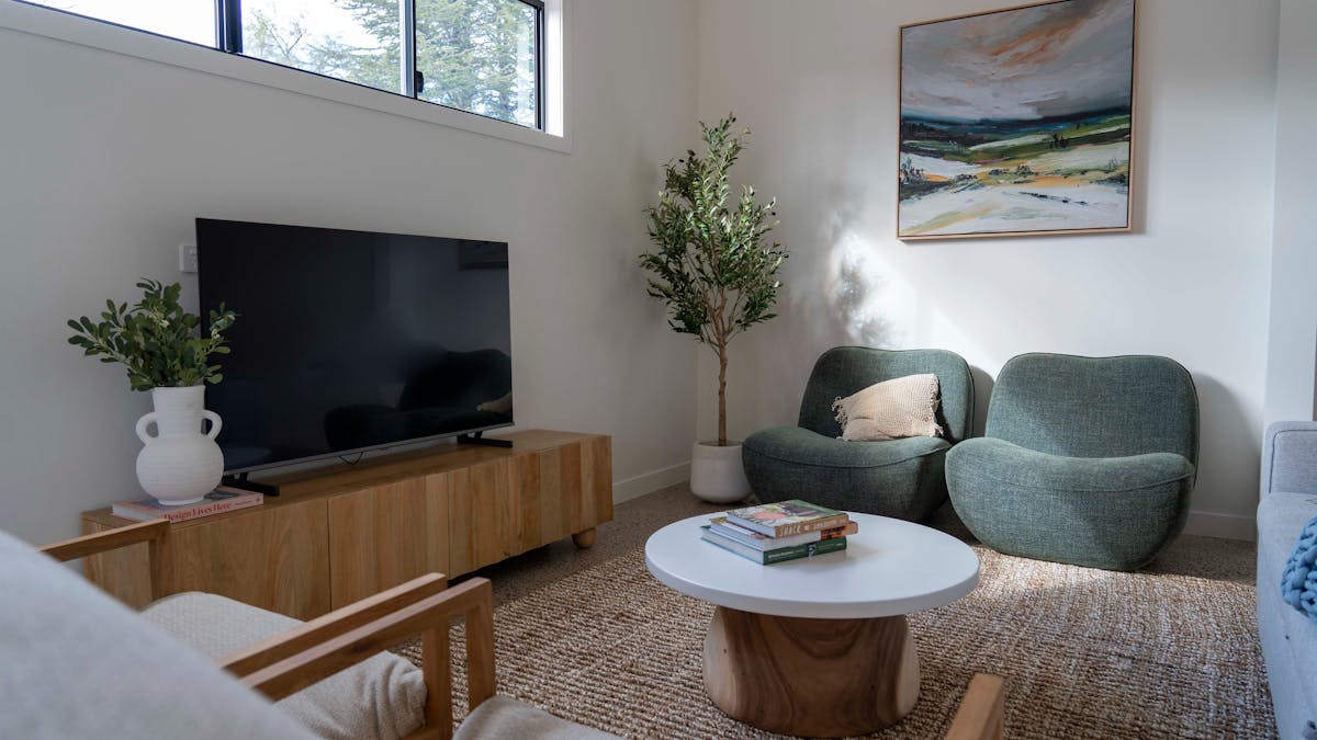 4 lounge chairs and a sofa with a timber coffee table and painting of landscape.