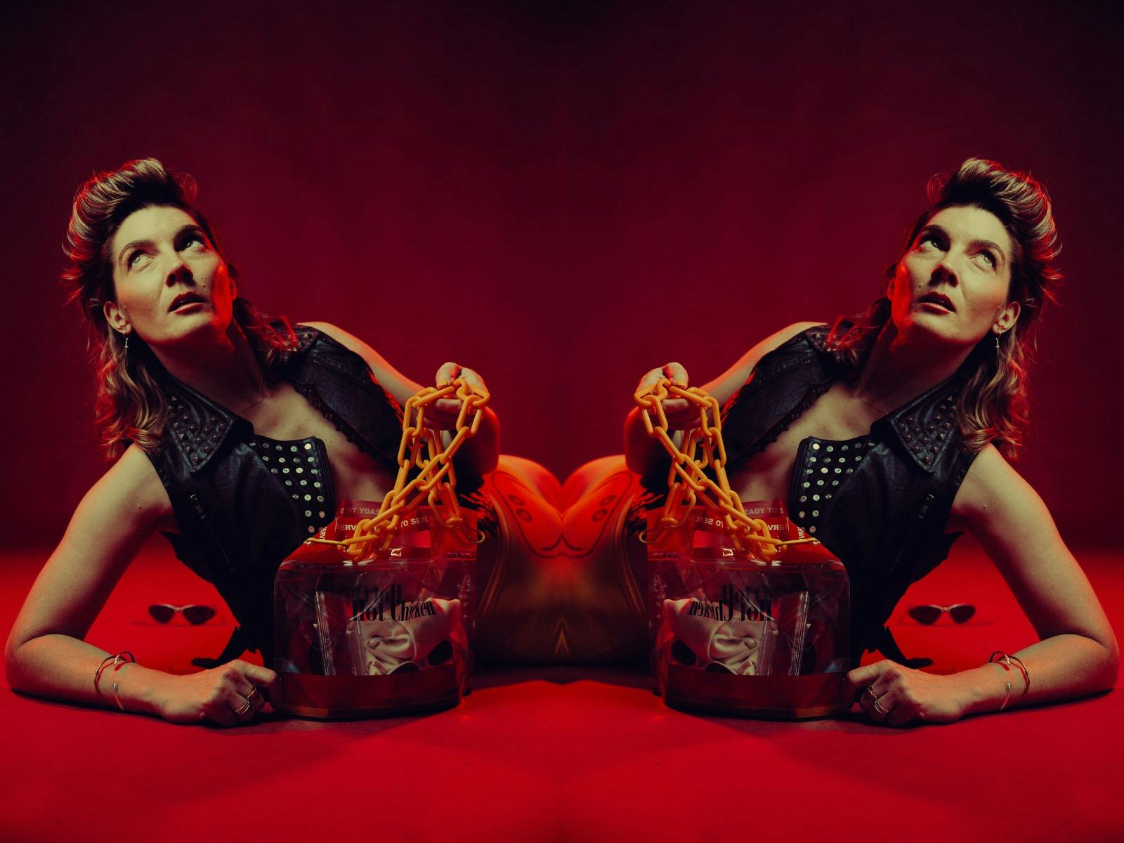 imaged of a woman laying down propped up one her right elbow while holding a hot chicken handbag.