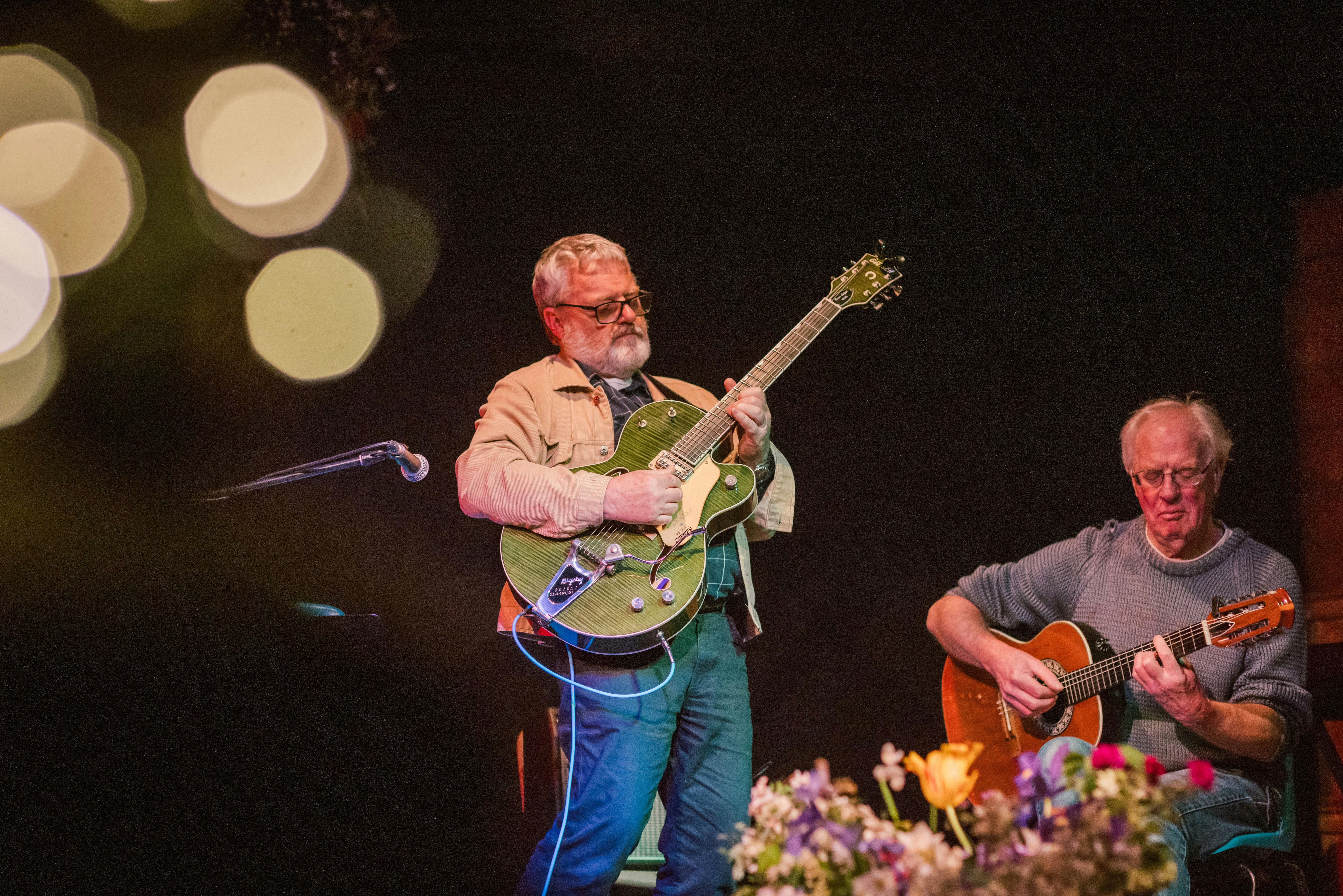 Two men are playing guitars on stage.