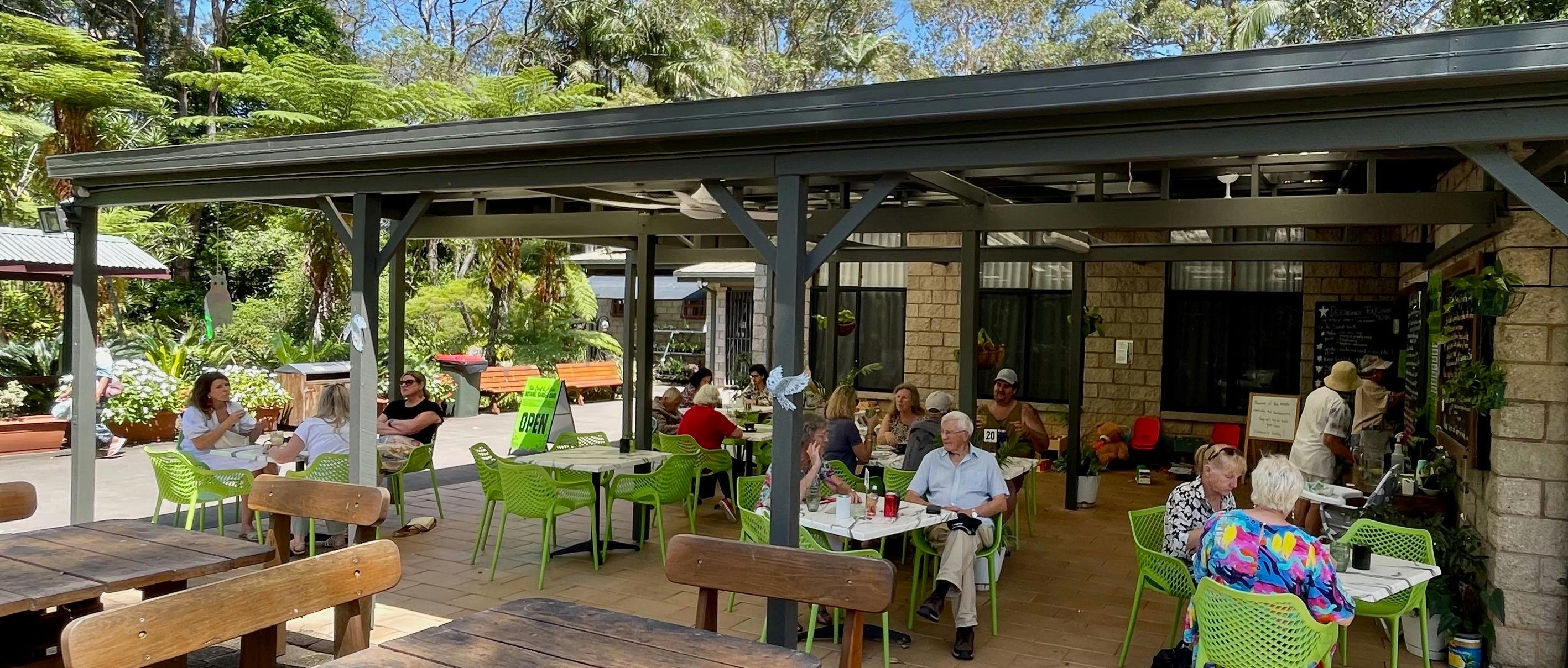 Visitors seated at undercover cafe tables enjoying food and drink