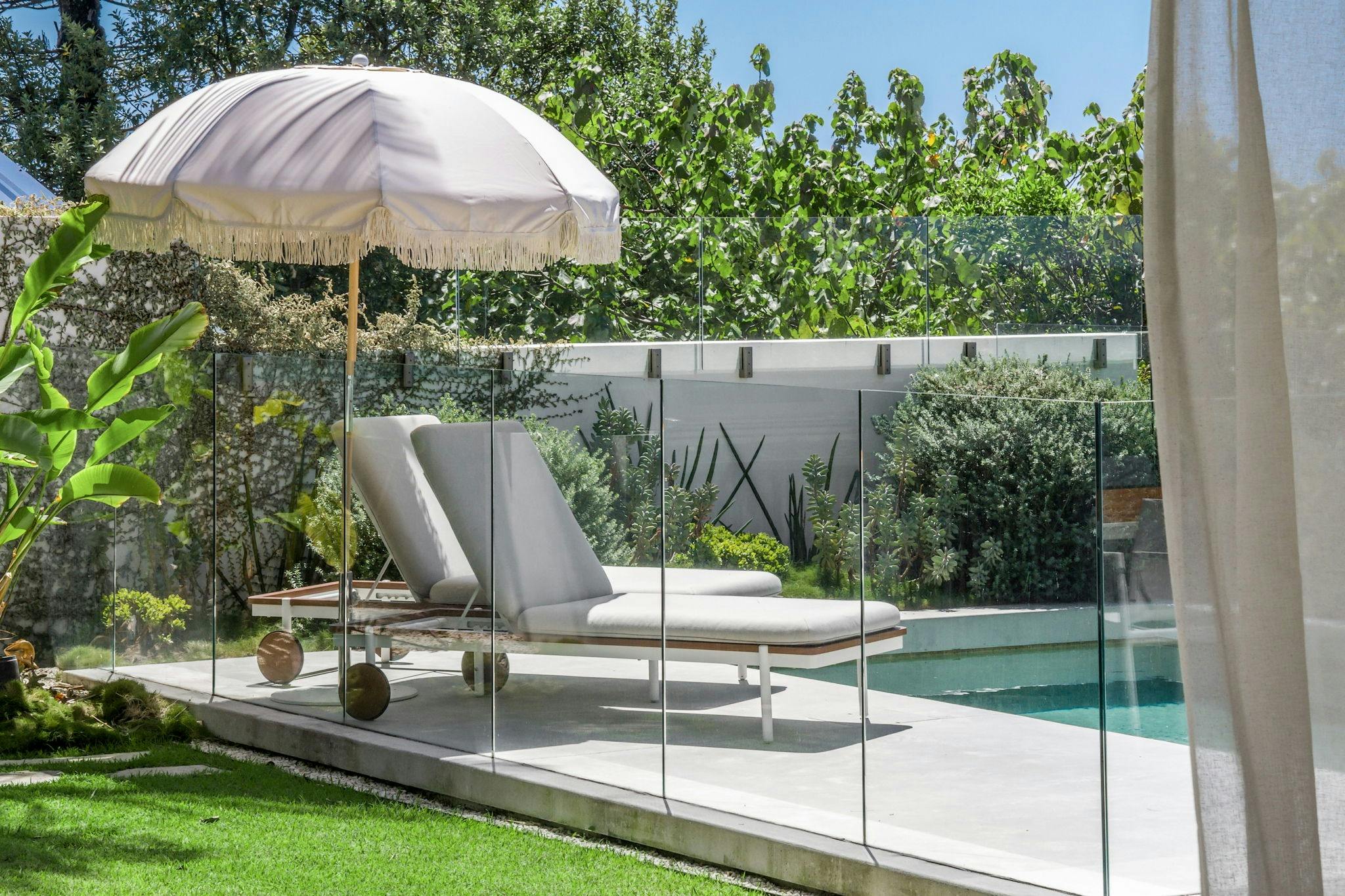 休閒泳池區設有泳池遮陽傘，周圍環繞著躺椅和鬱鬱蔥蔥的綠樹