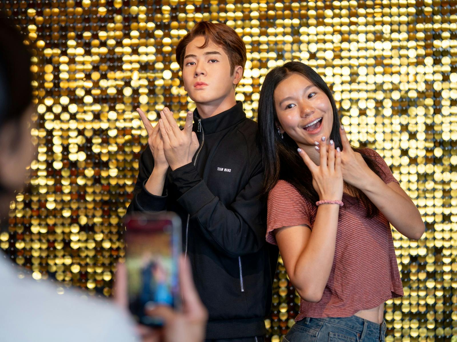 Fans posing with Jackson Wang's wax figure