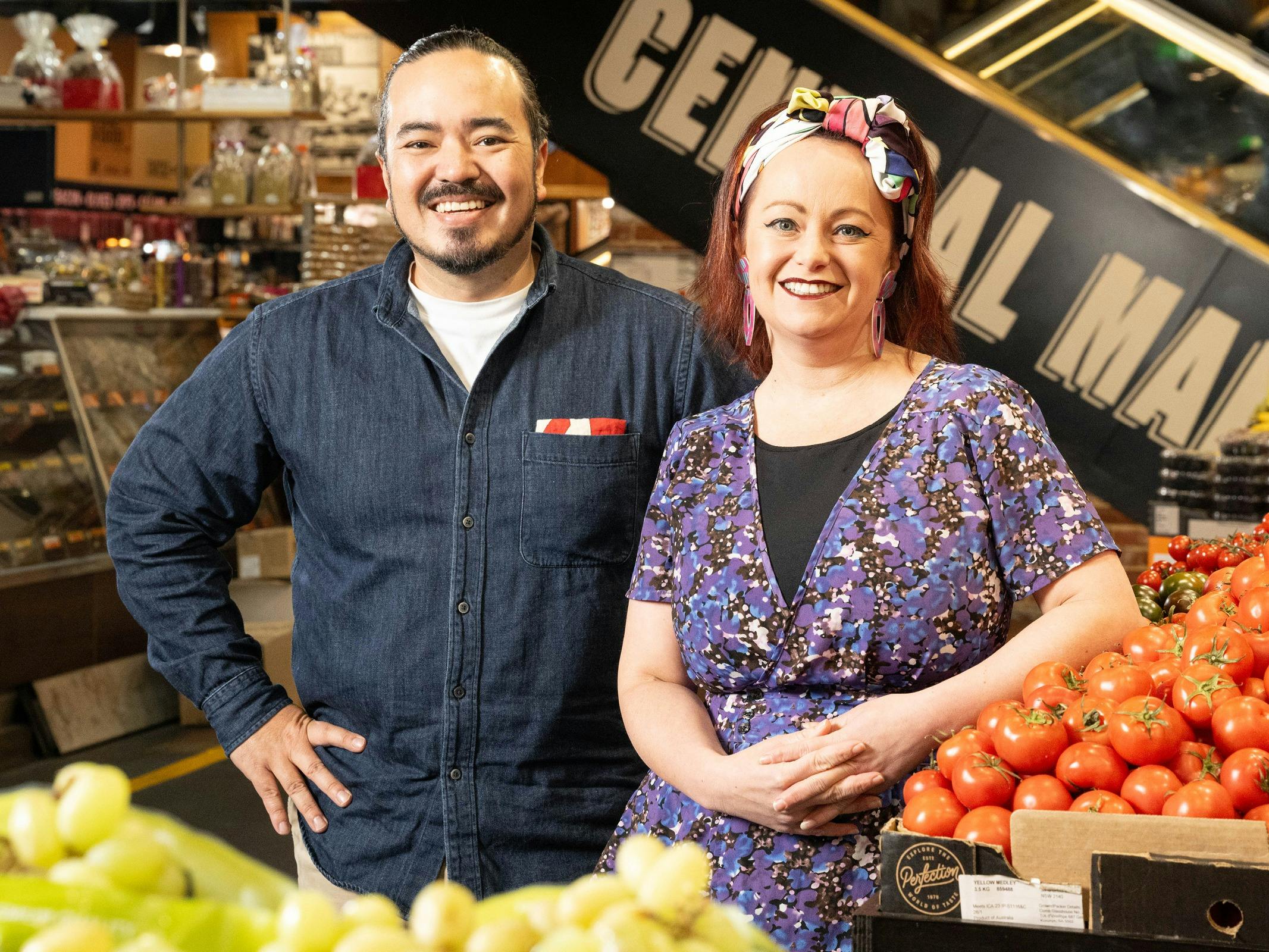 Adam Liaw and Katie Spain standing together surrounded by fresh produce