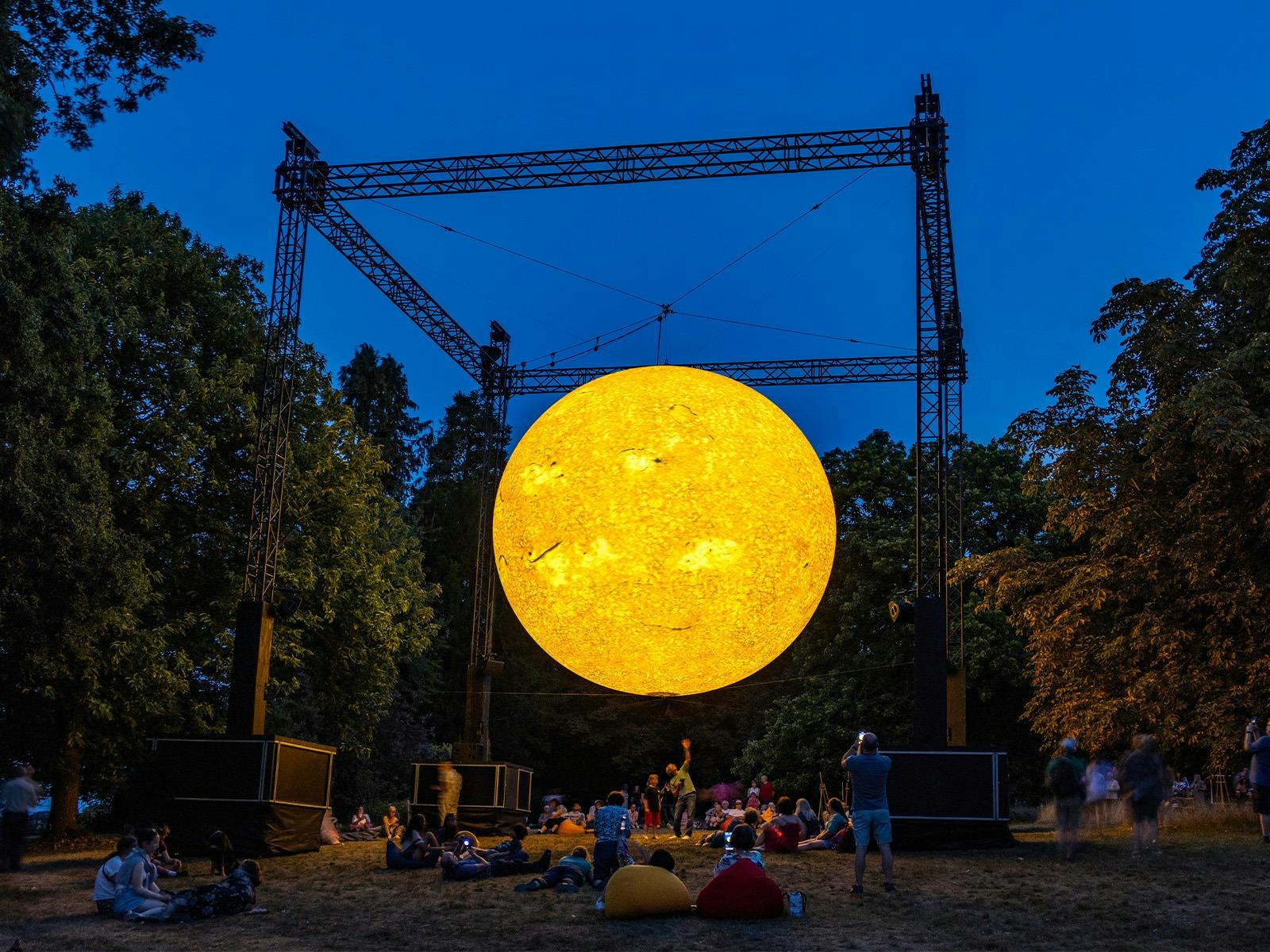 A fake sun hovering over people in a park