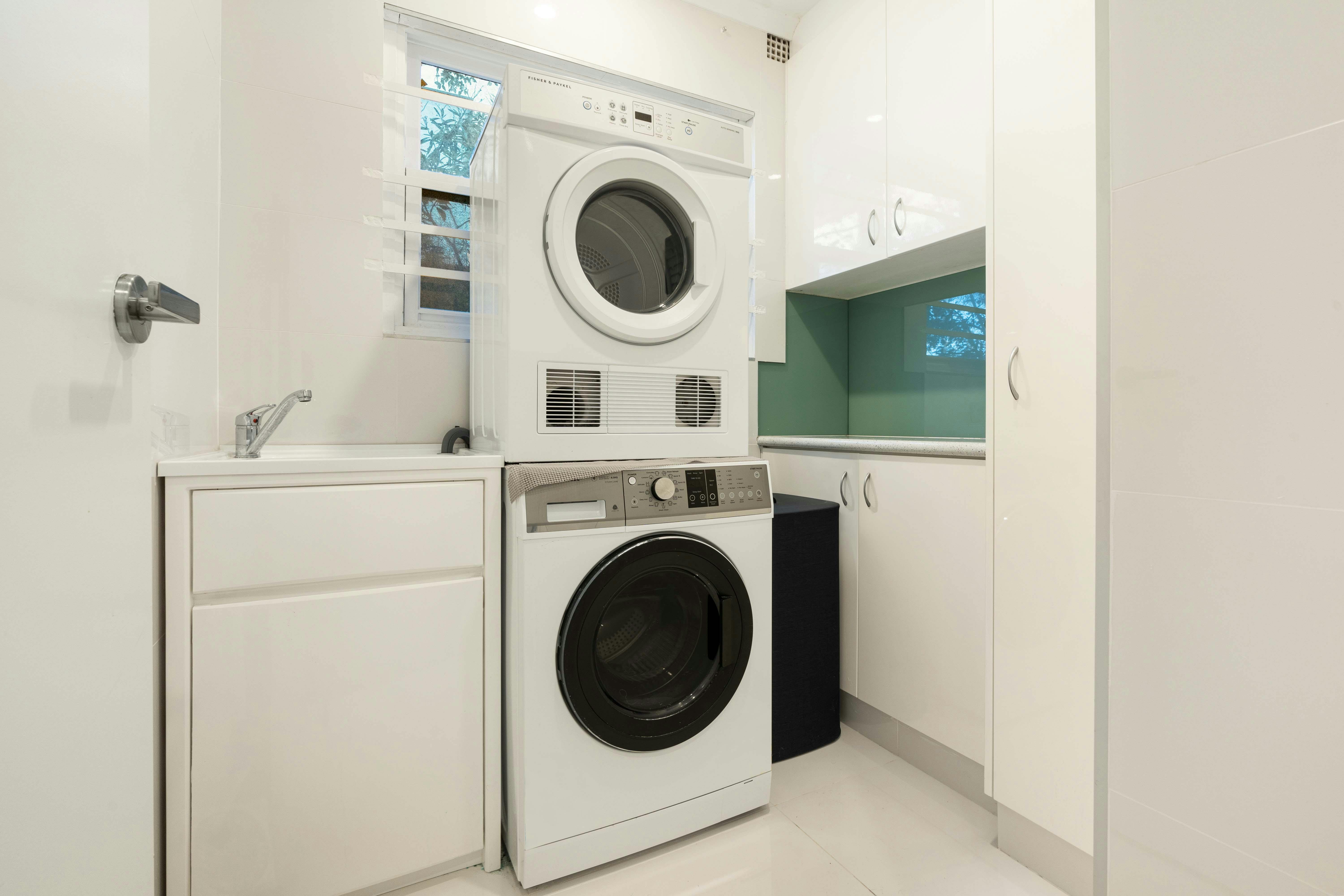 Laundry room with stacked washer and dryer, and built-in storage.
