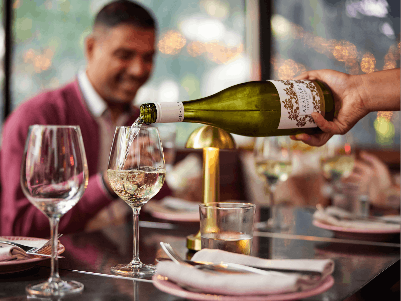 Waiter pours wine for guests at outdoor dining area