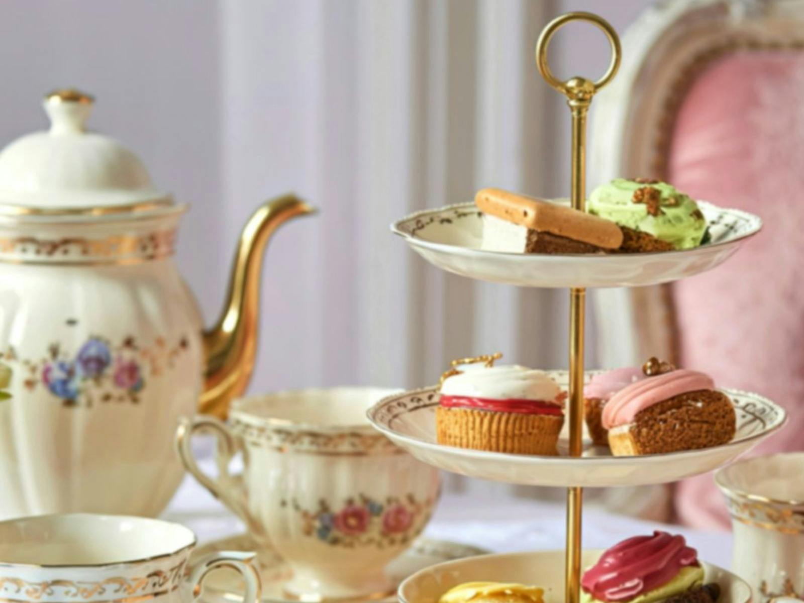 pretty high teas setting with cakes, biscuits and pastries with elegant china wear and teapot
