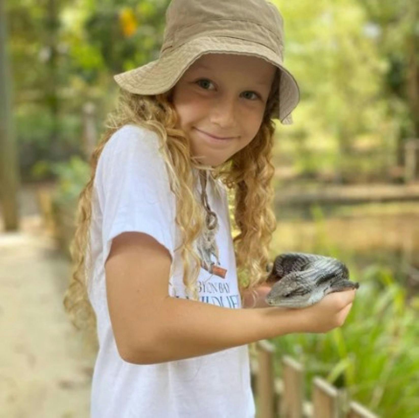 A young girl with a blue tongue lizard in her arms