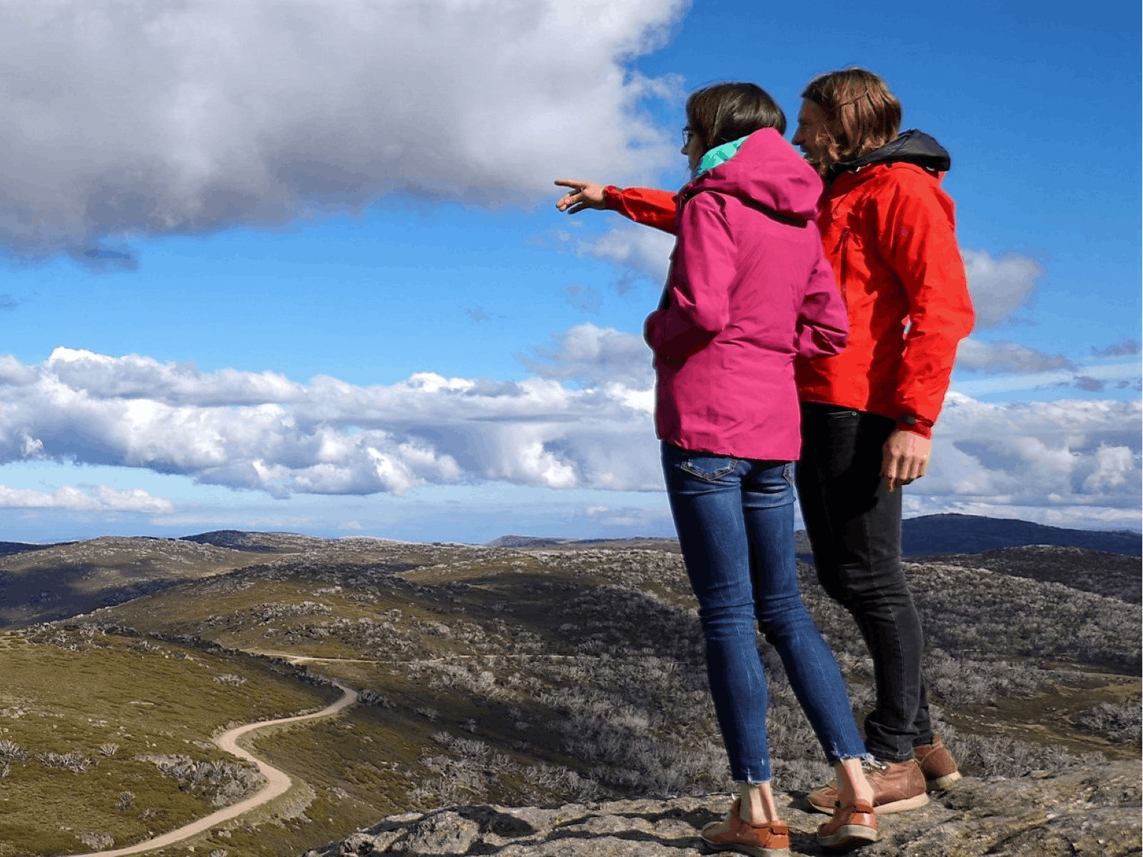 Couple standing on top of Mt Mckay looking across the Bogong High Plains and Rocky Valley Dam