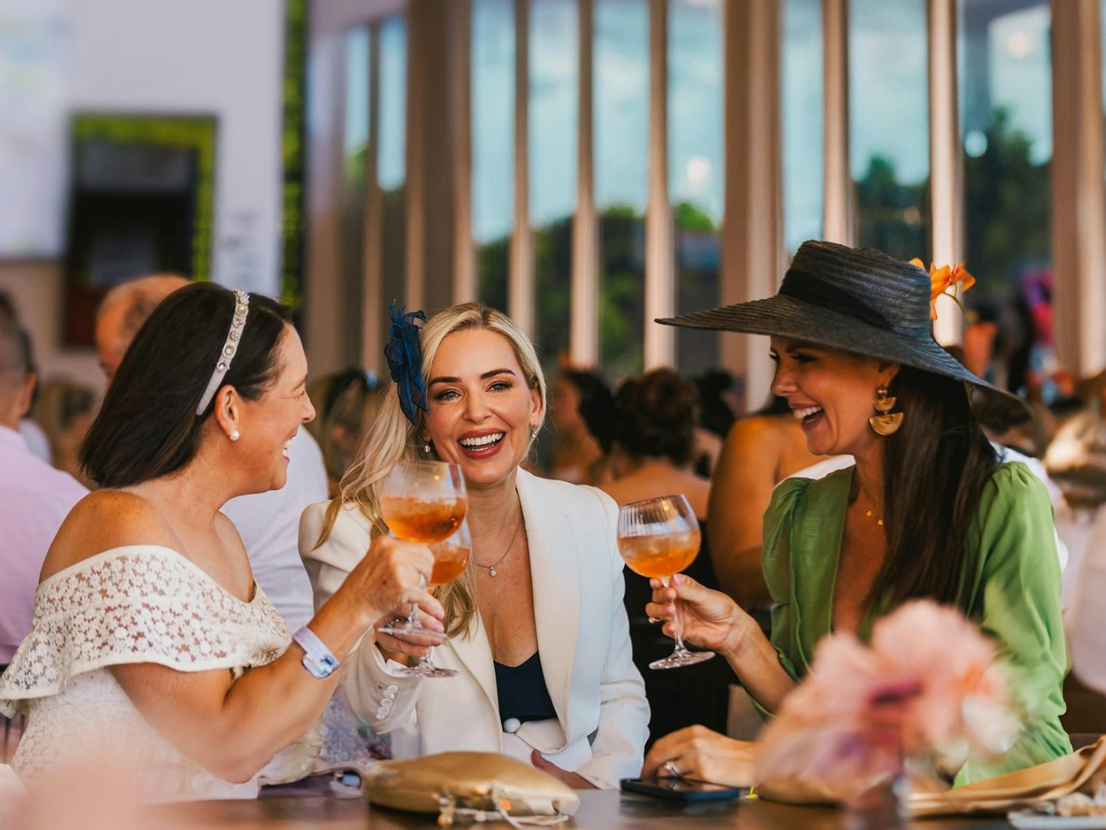 Three ladies enjoying a beverage and sharing laughs at EVA Air Ladies Raceday