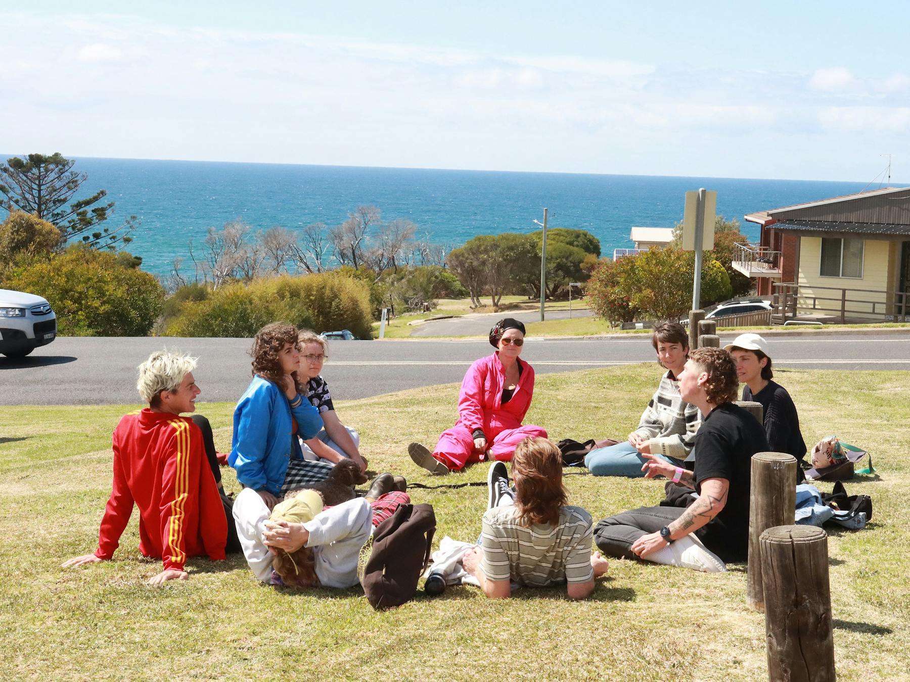 Audience members at the festival sit on the grass with the stunning ocean backdrop