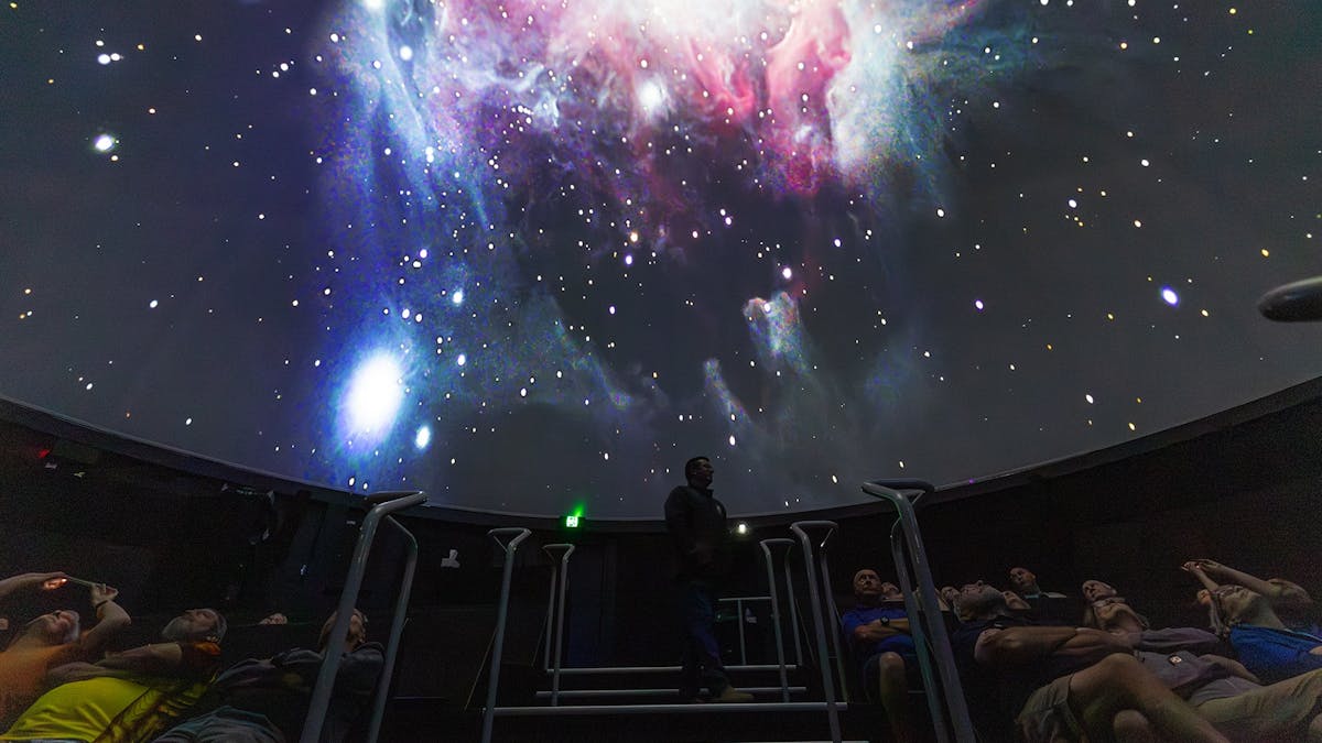 Inside the planetarium, looking up the stairs at the presenter, with guests seated looking up