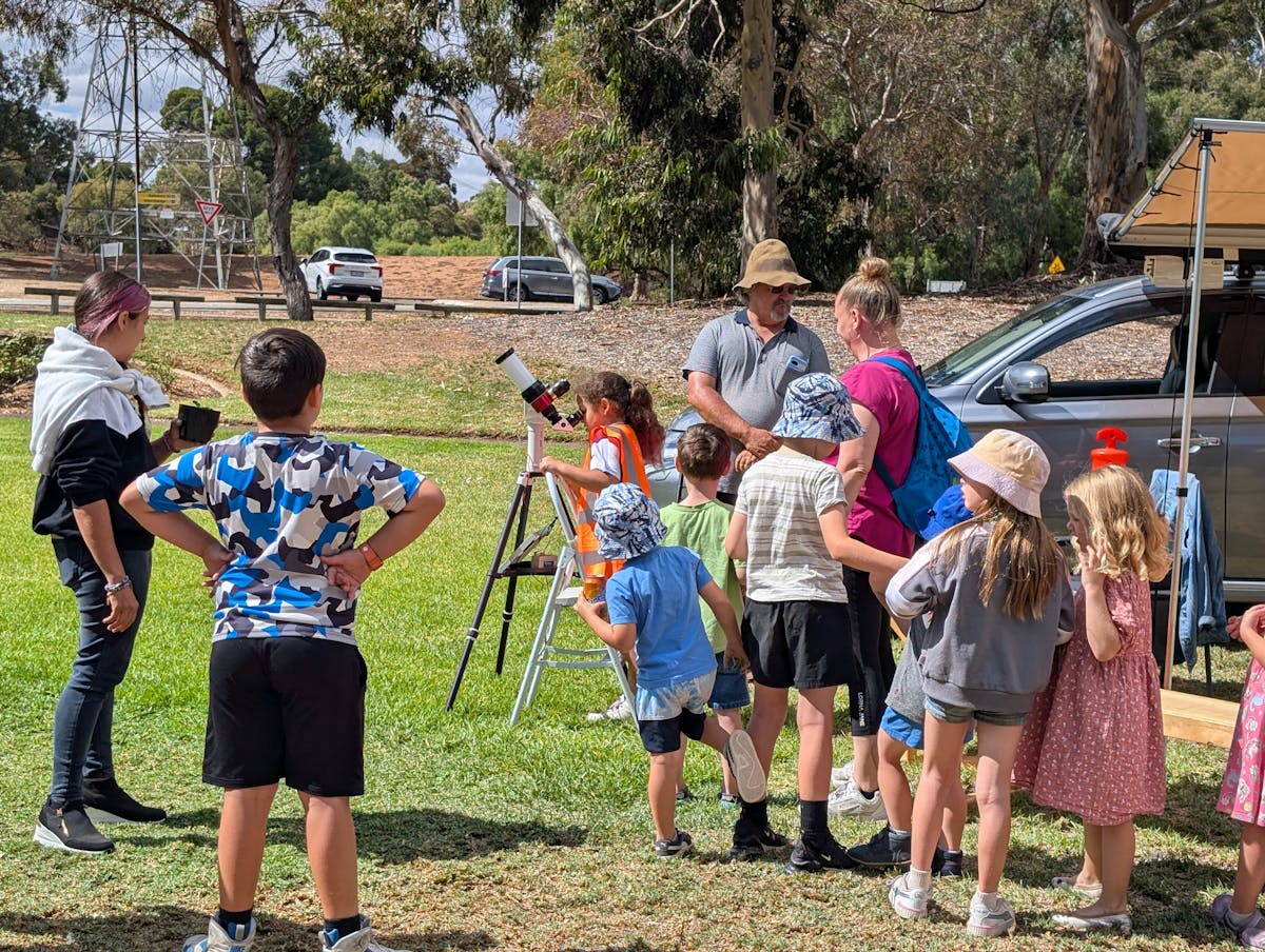 children taking turns to look through a Hydrogen-alpha Solar telescope