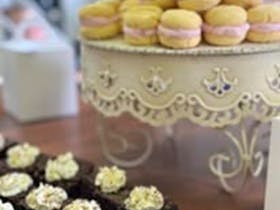 Melting moments biscuits with pink icing up on a stand and brownies with white icing. Delicious!