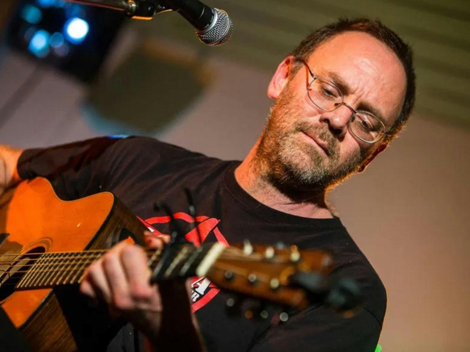 David Rovics playing a guitar in front of a microphone