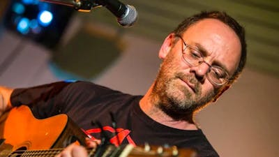 David Rovics playing a guitar in front of a microphone