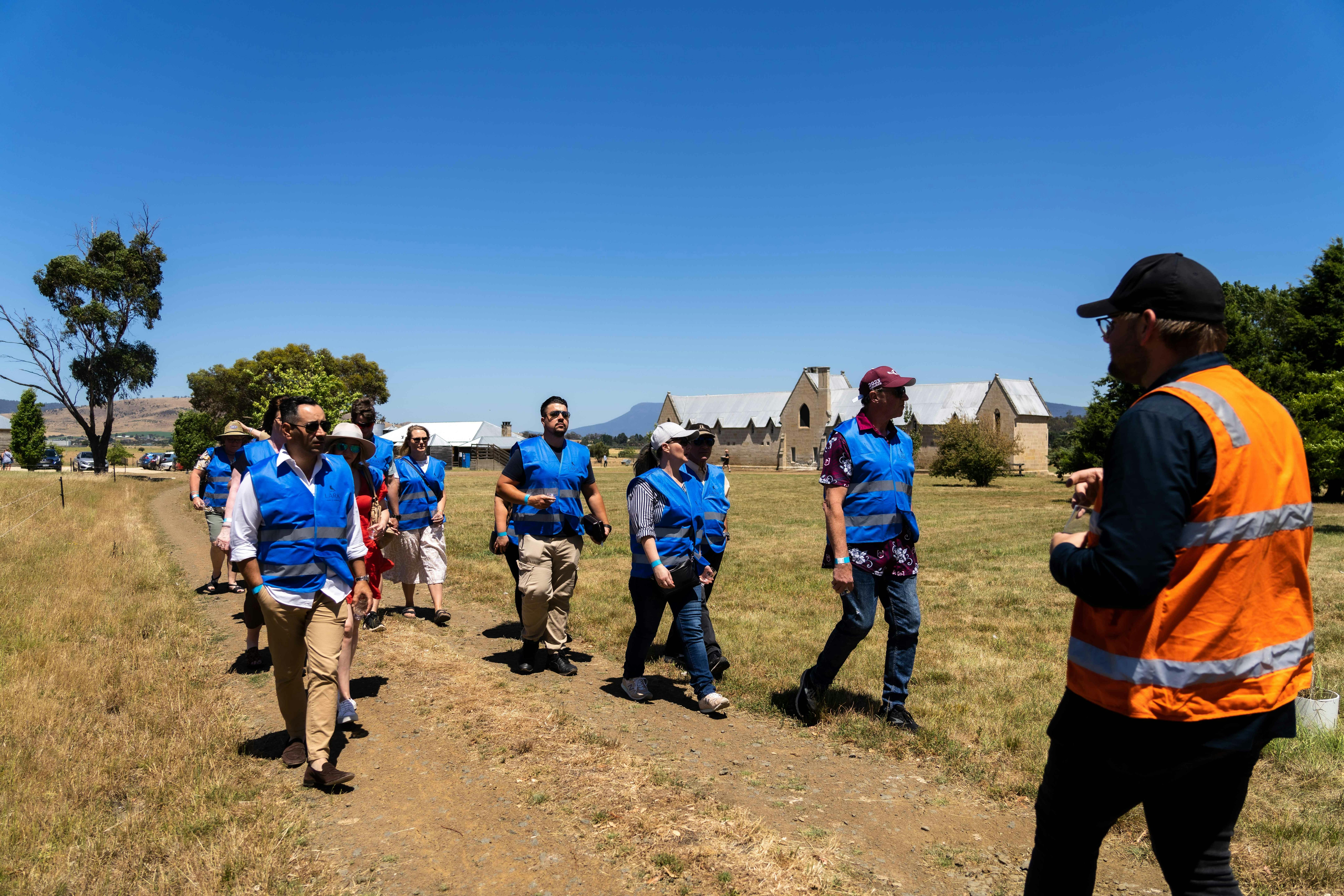 A group of people on a tour walking along a road with historic buildings in the background
