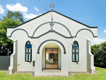 Shows the exterior of an old restored church on a sunny day. The church is white with black trim. Shows the exterior of an old restored church on a sunny day. The church is white with black trim.