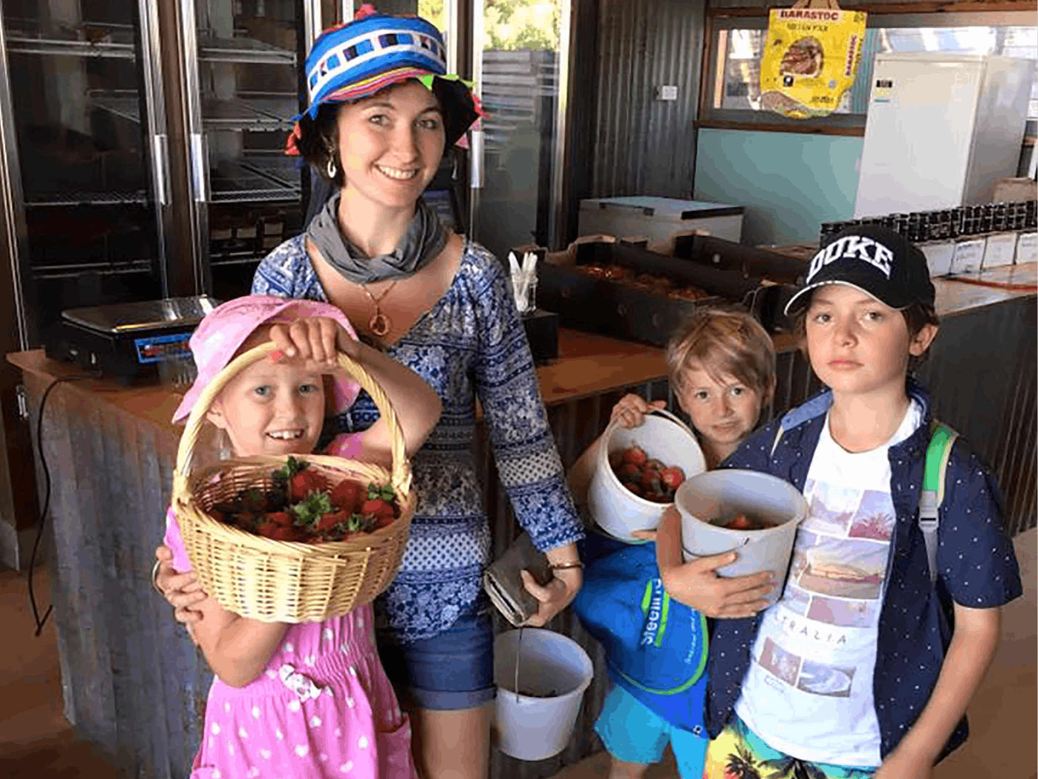 A family of U-pickers holding buckets full of strawberries