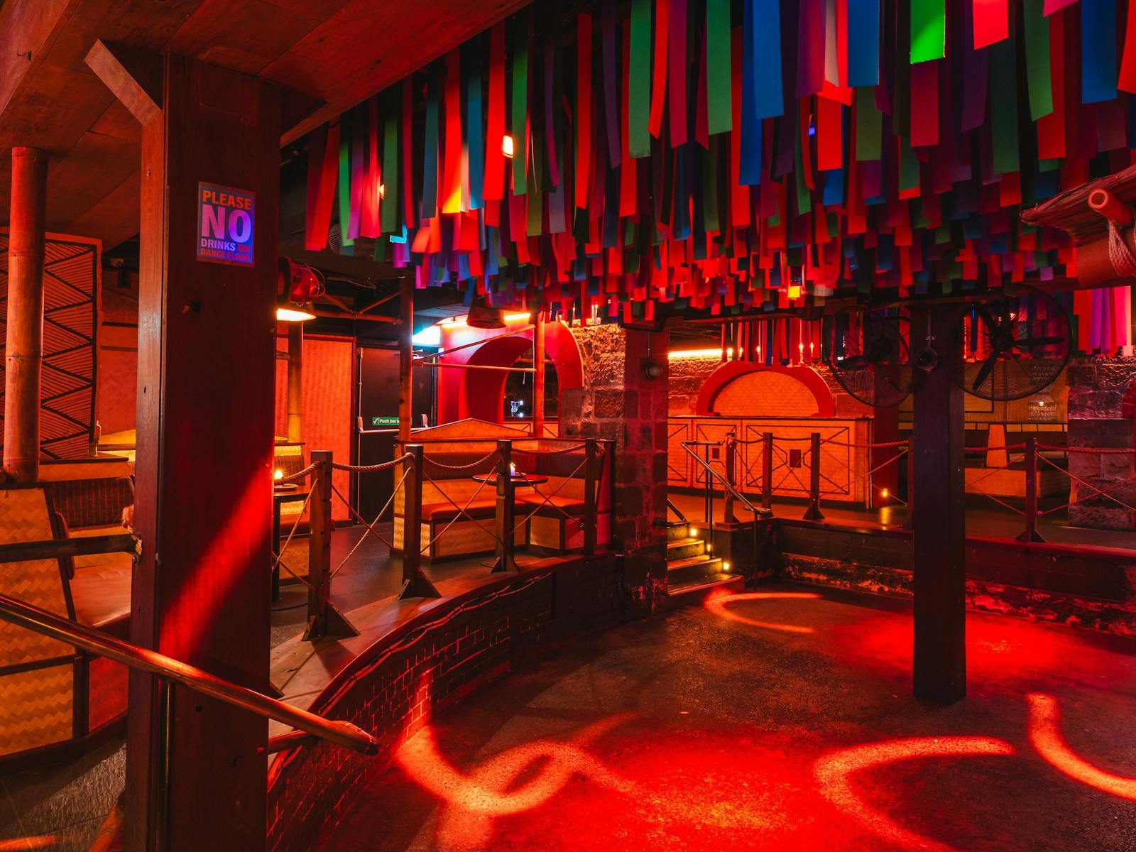 A nightclub interior with a sunken dance floor lit in red light