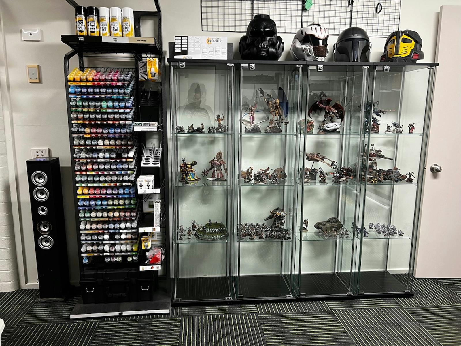 Paints and glass cabinets displaying painted miniatures and collectible helmets.
