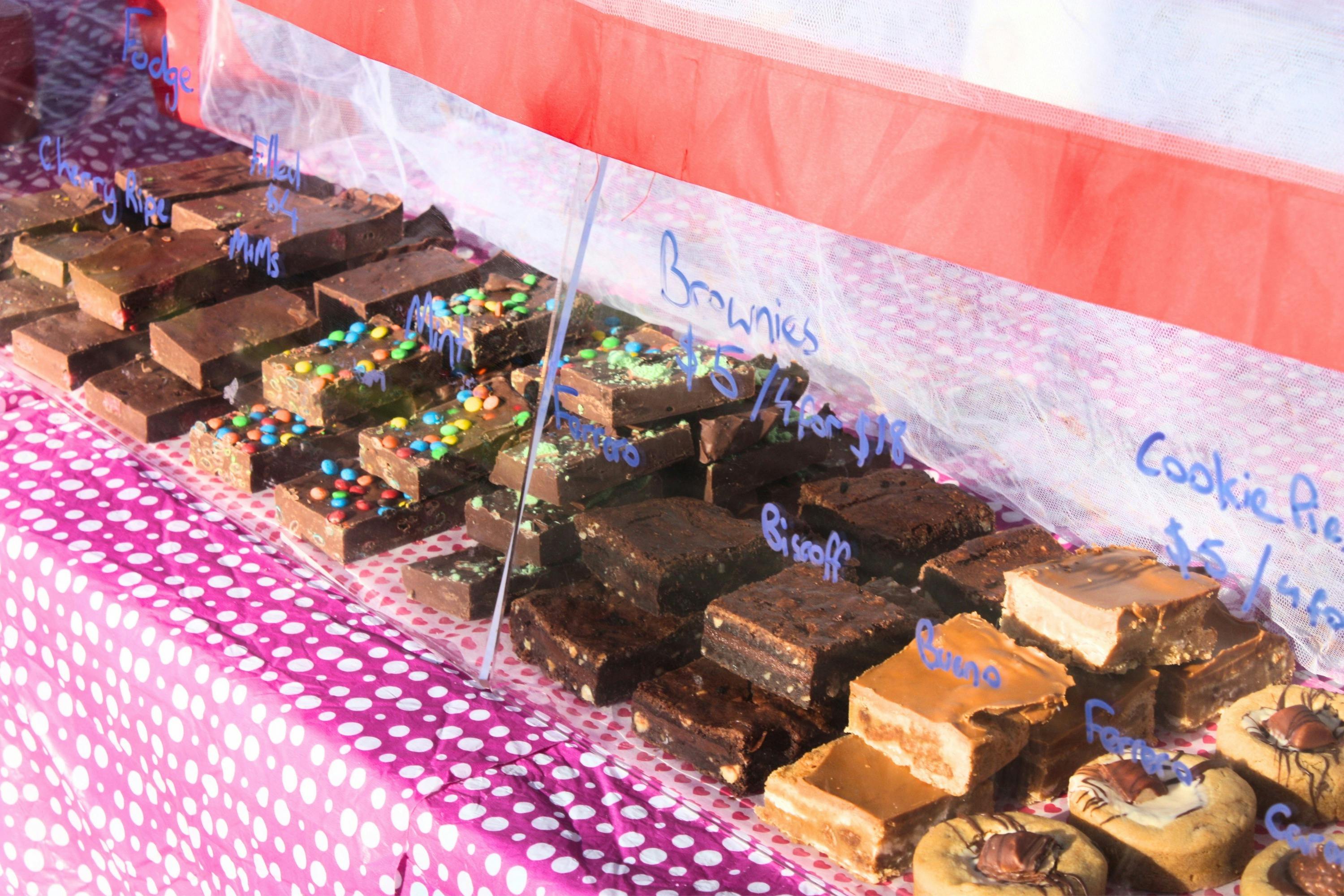 Rows of different kinds of brownies and slices in a stall display.
