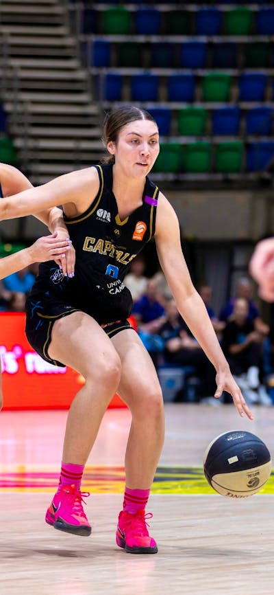 UC Capitals player driving to the basket for a layup during a WNBL game.