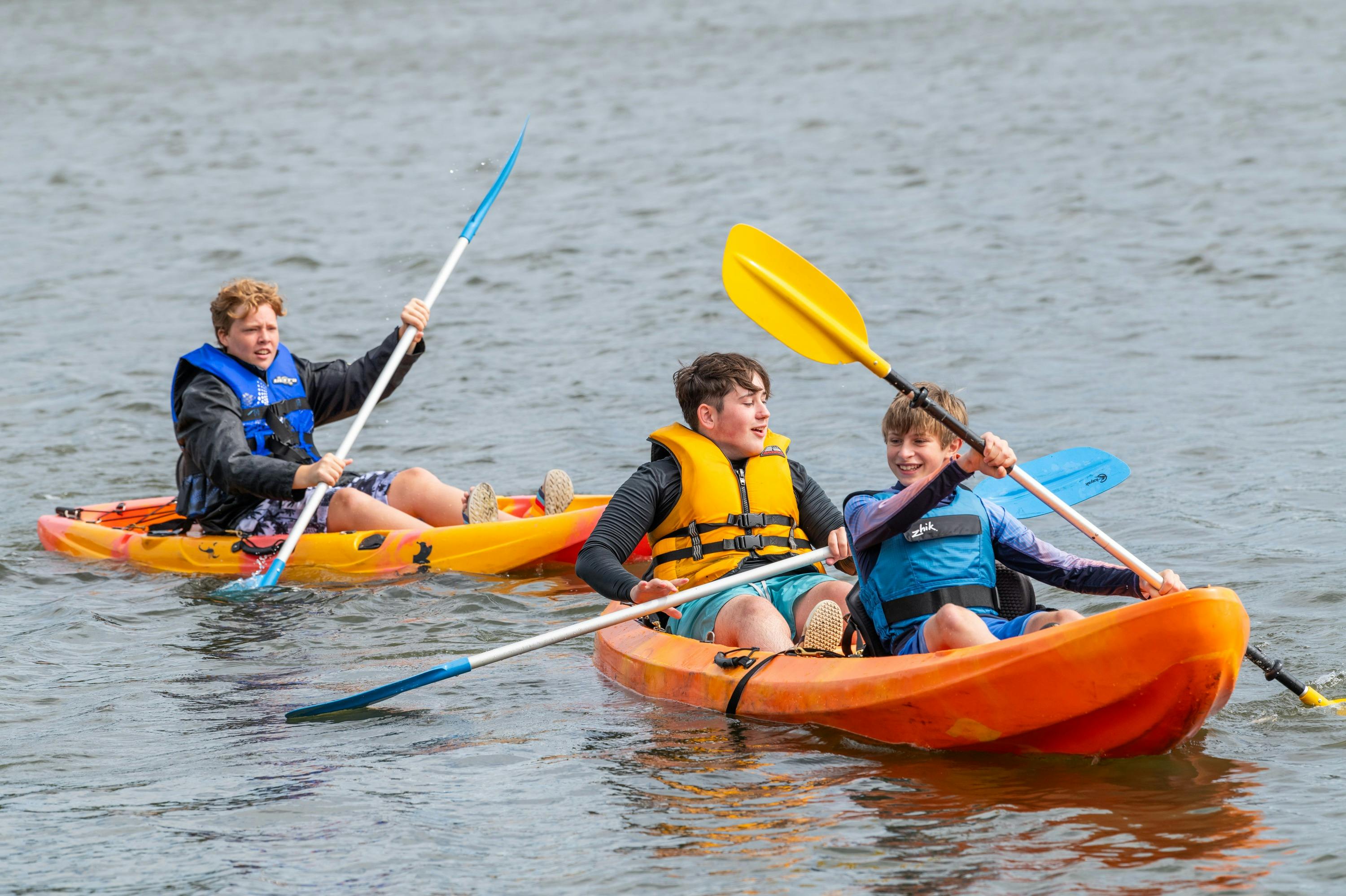 3 Male Youth on Double and Single Kayak in water
