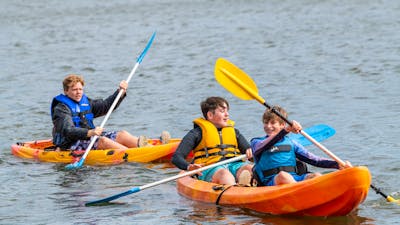3 Male Youth on Double and Single Kayak in water