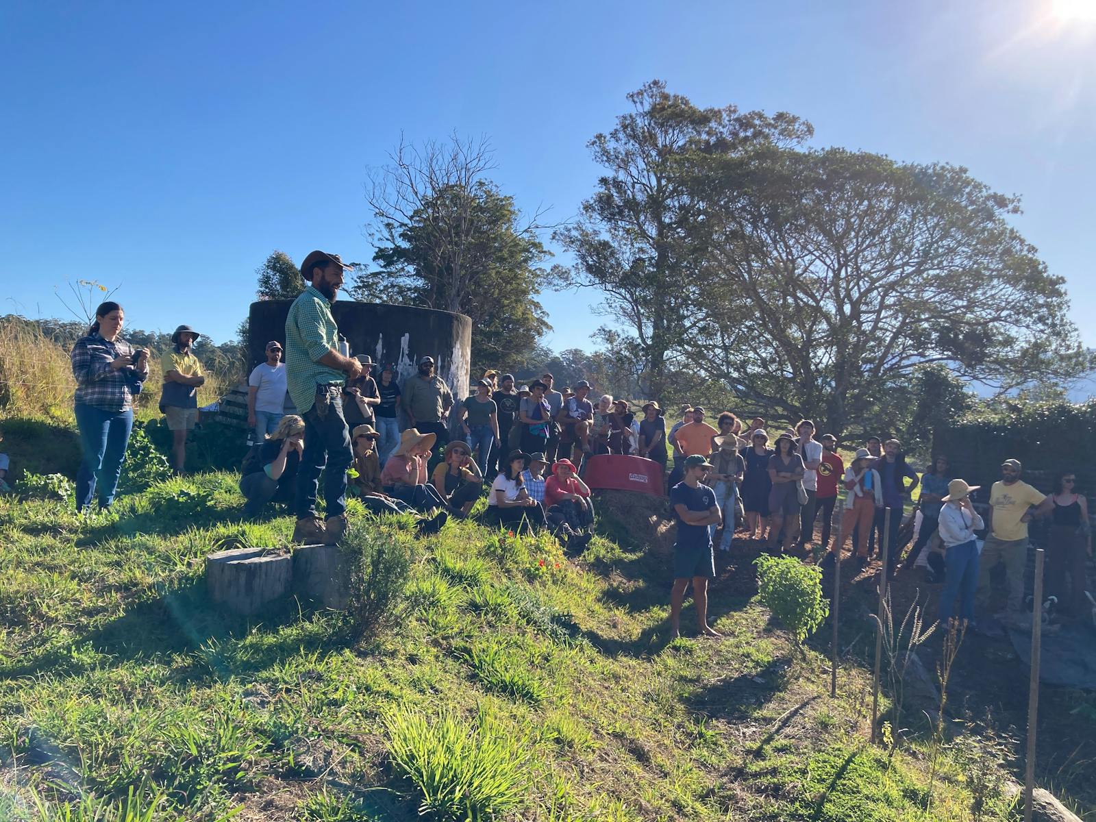 Talking to a crowd atop a hill that is cultivated