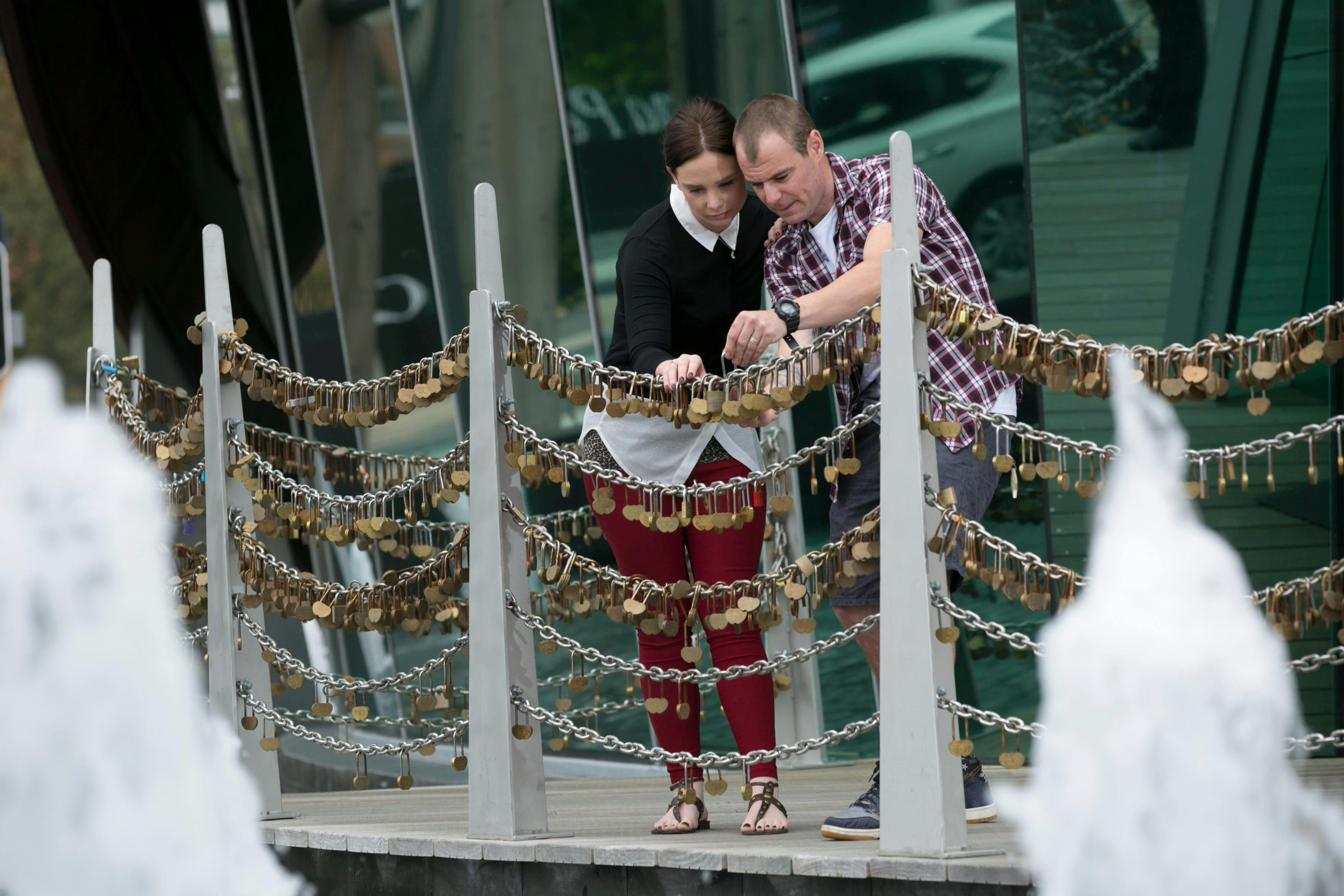 A couple lock their Love Lock onto the Love Lock Bridge out front of The Bell Tower