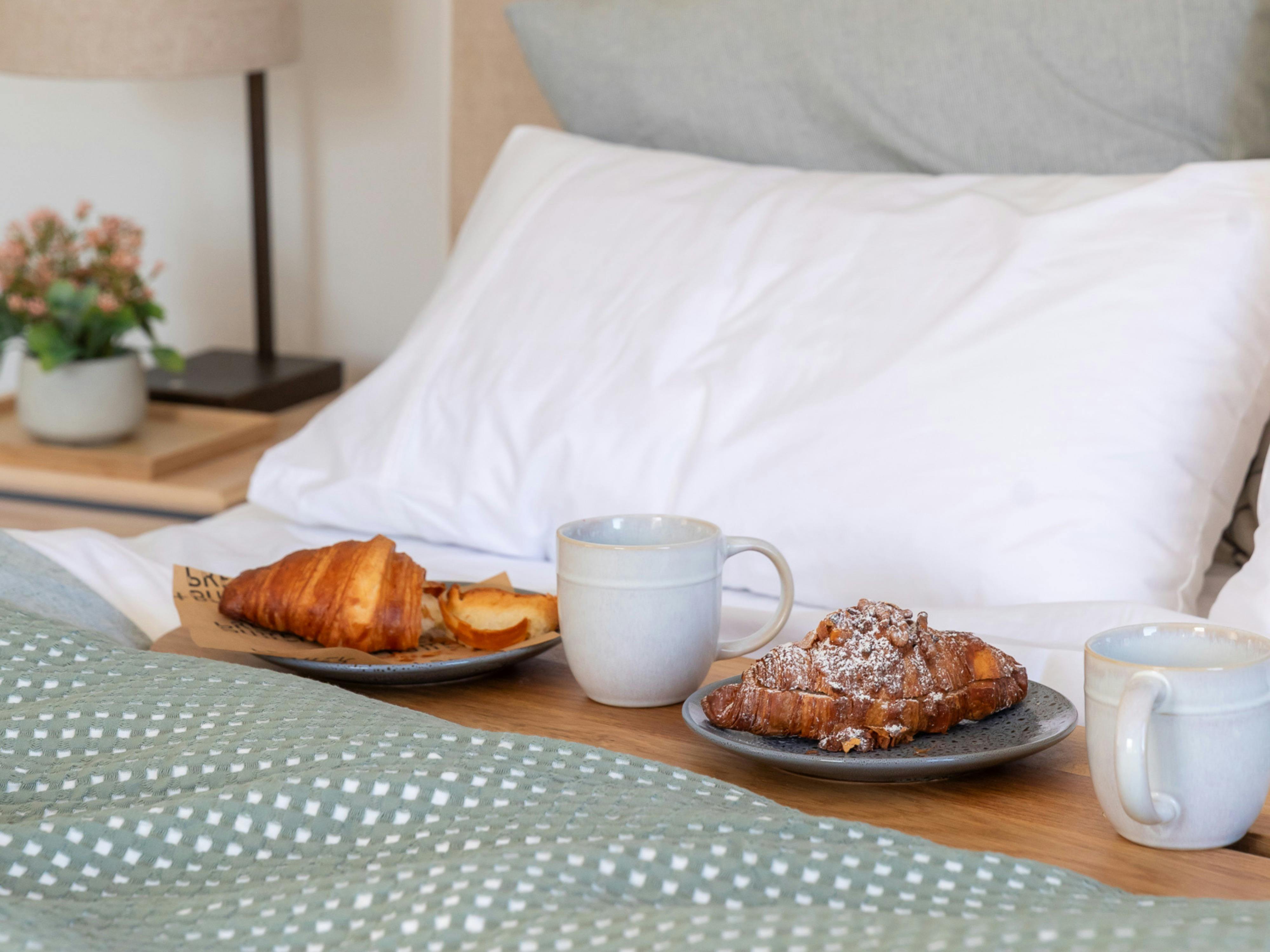 bed set with wooden serving board, coffee cup, plates and pastries